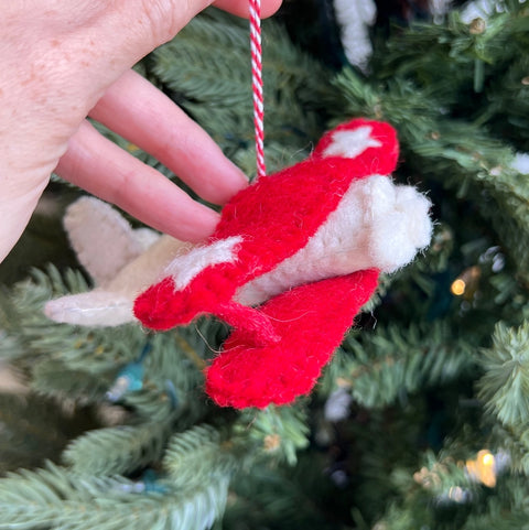 Felt wool red and white biplane ornament with white stars on it's wings and a red and white striped hang thread.