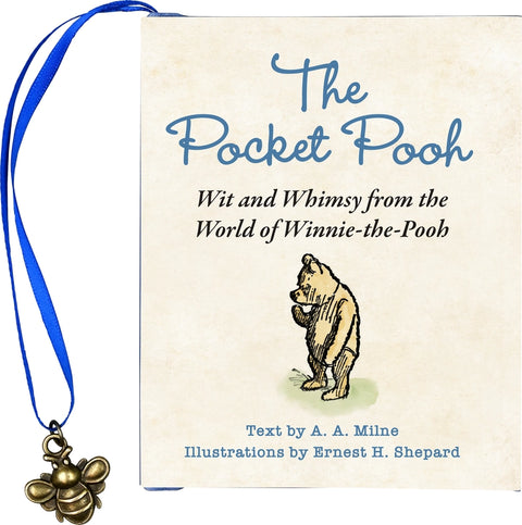 A book titled, "The Pocket Pooh" with a blue ribbon for a bookmark that has a bee charm attached to the end.