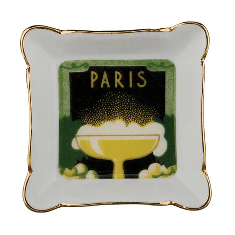 A small trinket dish with gilded edges. it is square shaped with scalloped corners, and on the inside of the dish is a green and yellow printed image of a cocktail glass. Over the top of the cocktail glass is the words Paris.