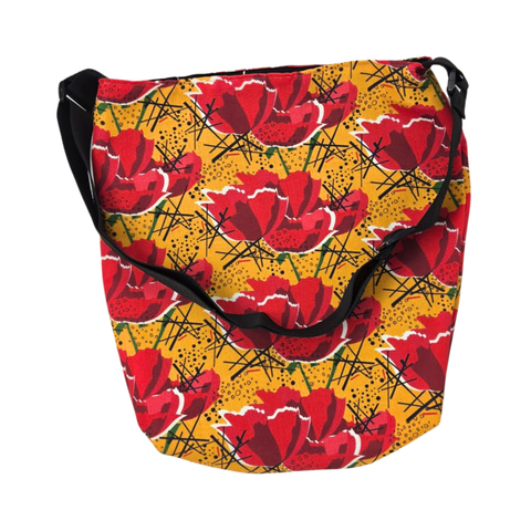n everyday bag adorned with a vibrant red poppy flower pattern on a golden yellow background and featuring a black strap. 