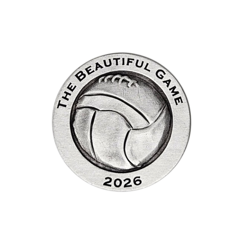 A pewter challenge coin depicting a soccer ball and the text, 'The Beautiful Game 2026' on it.