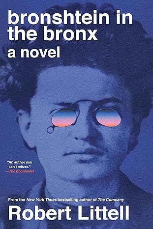 Blue toned book cover featuring a close up photograph of a man’s face wearing round glasses with reflective, tinted lenses. The image has a modern, stylized look.