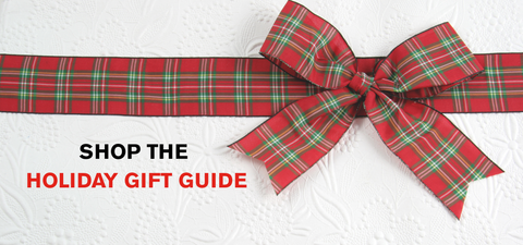 A festive banner with a red and green ribbon tied across a white background. In the bottom left corner is text that reads "Shop the Holiday Gift Guide"