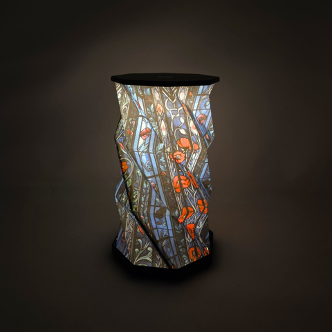 A decorative paper lantern with a blue and red stained glass style pattern of poppy flowers. This image displays it turned on.
