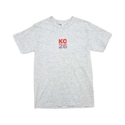 A light gray tshirt with KC26 in a small retro font on the front. The font is in blue and red.