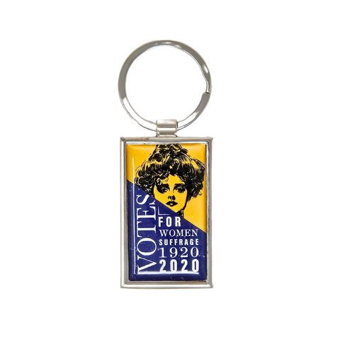 Small rectangular metal keychain featuring an illustration of a woman with a 19th century hairstyle at the top with a yellow background and the words Votes for women suffrage 1920, 2020 in white against a blue background at the bottom.