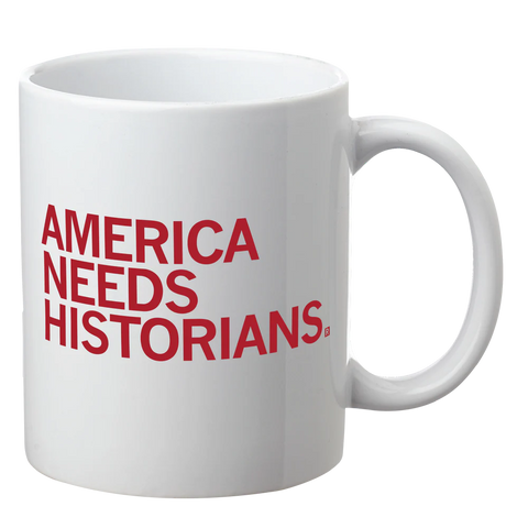 A white mug with dark red text that reads, "America Needs Historians".