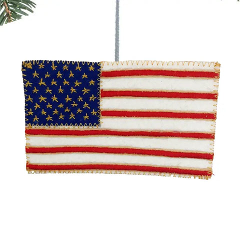 Image of an ornament. It is an American flag with yellow stitching around the edges.